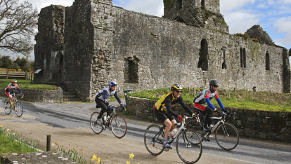 Cycling group passing ruined church, Limerick